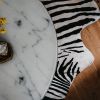 marble table with flowers vase placed on parquet floor in stylish room
