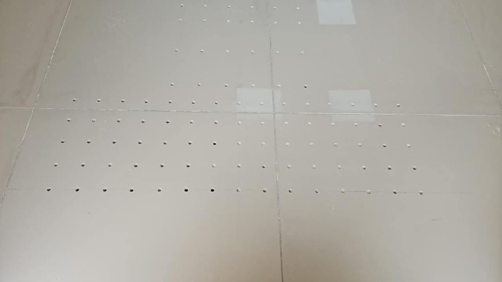 A flat, light-colored surface with evenly spaced holes arranged in rows and columns.