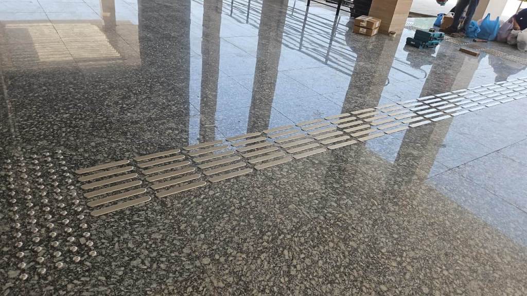 A polished granite floor featuring a series of metal plates arranged in a linear pattern, with areas of reflection visible due to the surface shine.
