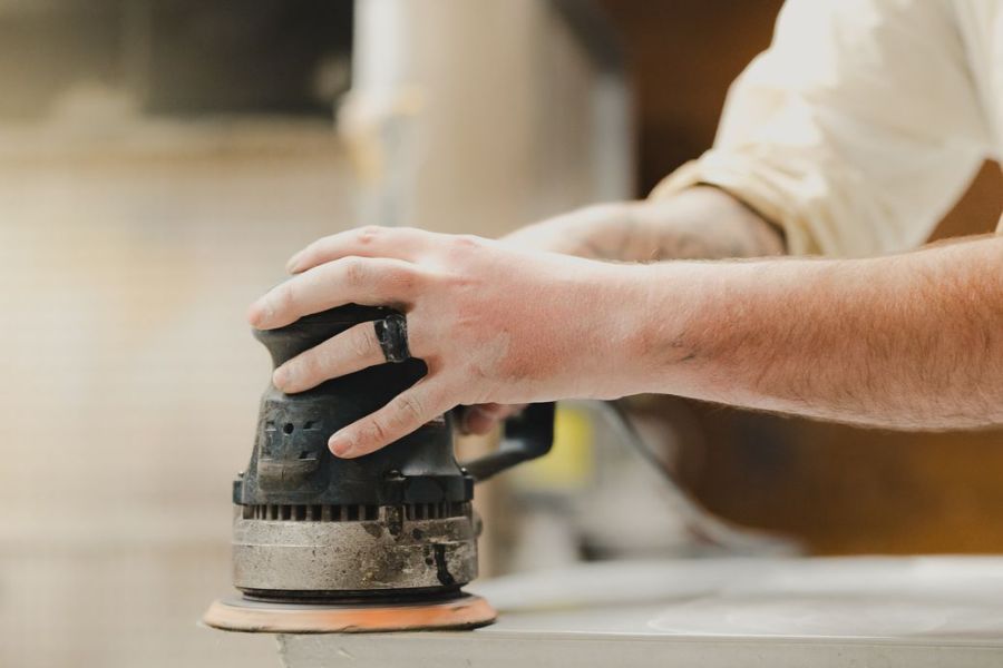 carpenter using orbital sander in workshop