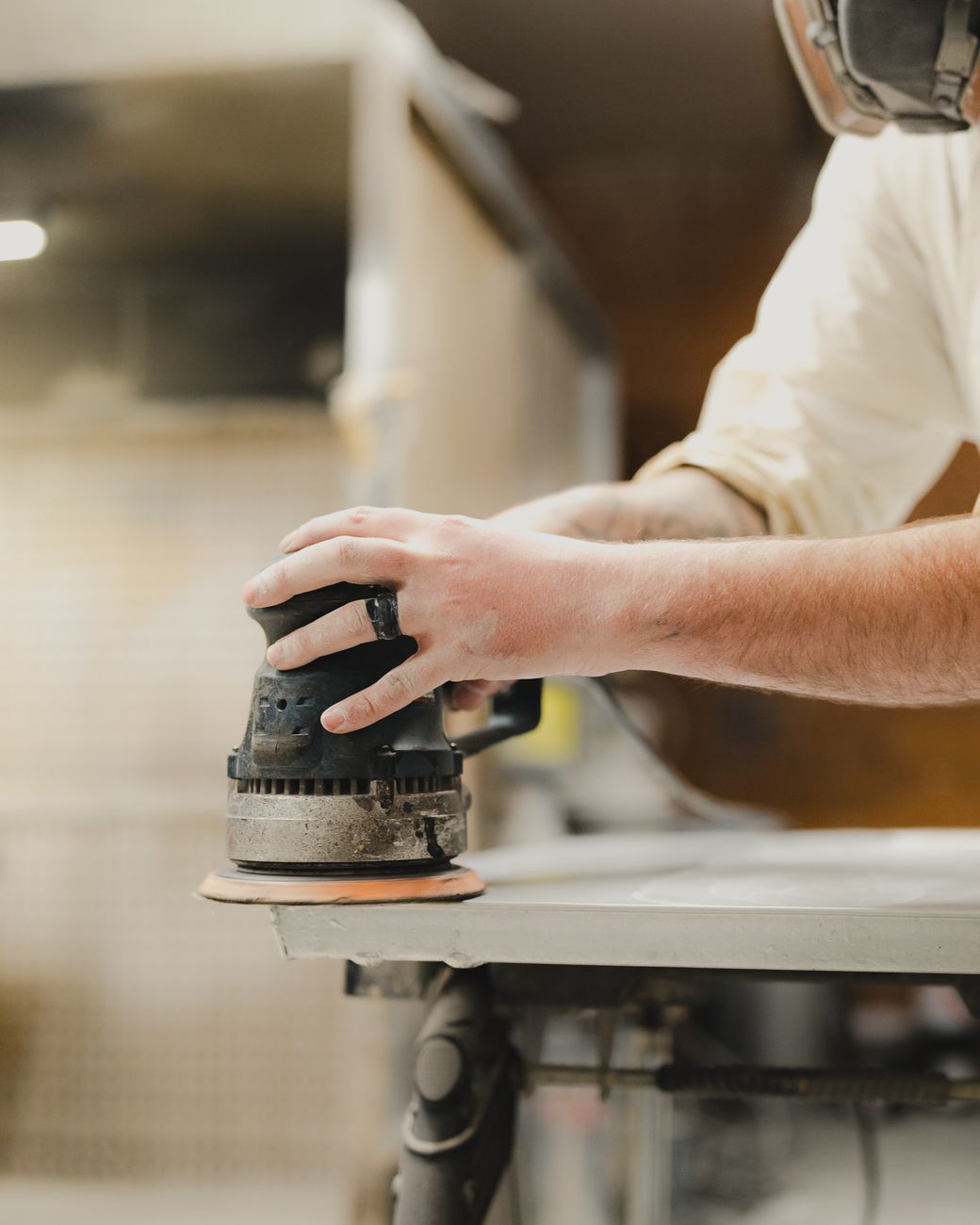 carpenter using orbital sander in workshop